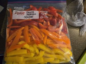 Red, orange, and yellow bell pepper strips in a gallon-size freezer bag.